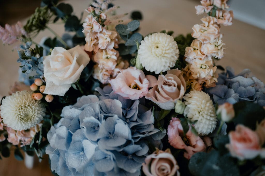 Muted pastel tones of blue, ivory and pink mix together to create a floral bouquet that matches one of the popular winter wedding trends this year.